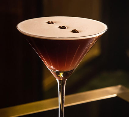 cocktail3 A martini glass filled with a dark brown cocktail topped with a creamy foam and garnished with three coffee beans.